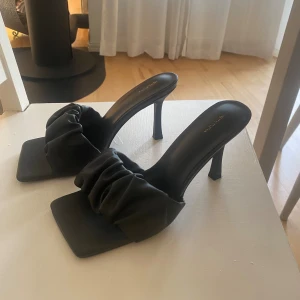 Svarta klackar/mules - Svarta klackar/mules, i läderimitation från Pretty Littel Thing. Storlek 5, motsvarande strl 37. Använde inomhus en gång. Mycket gott skick!!! Klackhöjd: 9cm Hör av dig vid ev frågor!!🫶🏼🍸💖
