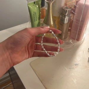 Silverfärgat pärlarmband - Säljer ett stilrent armband med silverfärgade pärlor. Perfekt för att ge en elegant touch till vilken outfit som helst. Armbandet är elastiskt och passar de flesta handleder. Perfekt för både vardag och fest!