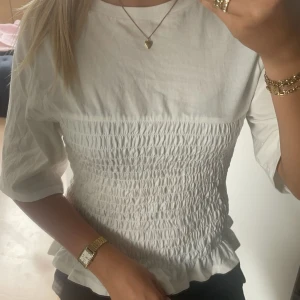 Smockad topp vit  - Jättesöt populär smockad topp från H&M! Skicket är mycket bra, inga synliga tecken på användning. Toppen är i storlek M men passar mig som brukar ha XS/S. Slutsåld på hemsidan! Hör av dig vid frågor eller önskemål om fler bilder🤍
