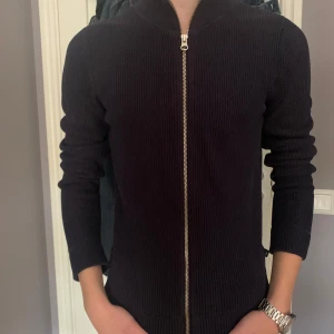 Svart ribbad tröja från Boomerang - Säljer en stilren mörkblå ribbad tröja från Boomerang i storlek XS/S. Tröjan har en dragkedja framtill och är perfekt för både höst och vinter. Den är långärmad och passar bra till både vardag och fest. Superbekväm och i bra skick!