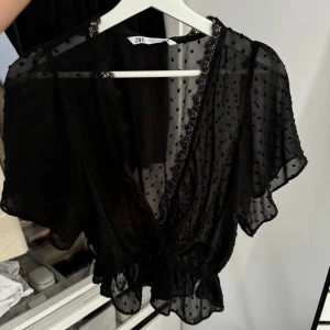 Svart blus - En fin svart tunnblus med öppning vid brösten. Bra material och skick