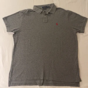 Grå Ralph Lauren piké  - En jätte trevlig Ralph Lauren piké i grå storlek Xl men passar L om man vill ha lite lösare passform den är i fint skick förutom ett hål under en av armarna kom gärna med bud eller fråga om extra bilder👍