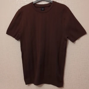 Brun ribbad tröja - Säljer en snygg brun ribbad tröja i storlek M. Den har korta ärmar och är perfekt för både vardag och fest. Tröjan är i bra skick och har en stilren design som passar till det mesta. Mycket mjuk och stretchig. Nyskick!