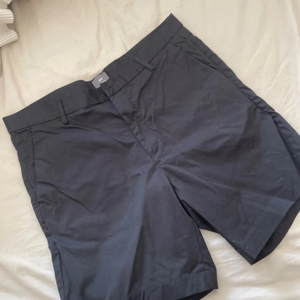 Stilrena svarta shorts från H&M. De har en klassisk design med knappar och dragkedja framtill. Perfekta för både vardag och lite mer uppklädda tillfällen. Shortsen har två bakfickor med knappar och är gjorda i ett bekvämt material. . Shorts.