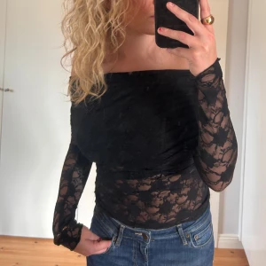 Svart spets topp - Säljer en superfin svart offshoulder topp i spets. Den är långärmad och har en tight passform som sitter snyggt på kroppen. Perfekt för festliga tillfällen! 🖤