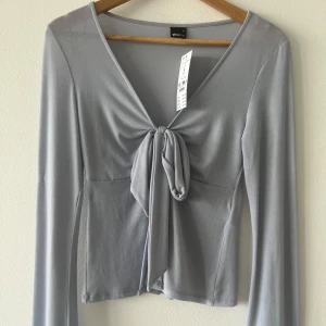 Helt ny supersöt slutsåld topp - Slutsåld superfin trendig blå v-ringad topp med knytning från Gina Tricot. Aldrig använd.