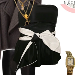 Svart topp med rosett - Snygg svart axelbandslös topp med ett band och en rosett i midjan. 