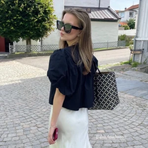 Svart blus från Gina Tricot - Snygg svart blus från Gina Tricot med puffiga korta ärmar och knytning framtill. Perfekt för en stilren look.