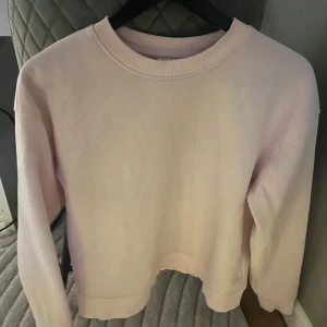 Ljusrosa tröja - Säljer en ljusrosa tröja med rund hals och långa ärmar. Tröjan har en enkel och stilren design, perfekt för en avslappnad look. Den är mjuk och bekväm att bära. Passar även strl S