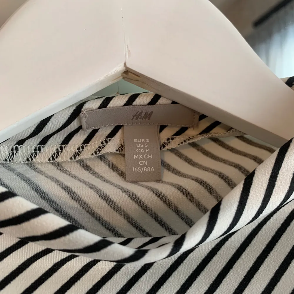 Säljer en stilren randig topp från H&M i svart och vitt. Toppen är ärmlös och har en draperad design på sidorna som ger en snygg detalj. Perfekt för en avslappnad men chic look.. Yläosat.