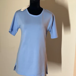 Ljusblå t-shirt från Calvin Klein - Säljer en stilren ljusblå t-shirt från Calvin Klein med korta ärmar och rund halsringning. T-shirten har en diskret CK-logga broderad på bröstet. Perfekt för en avslappnad look.