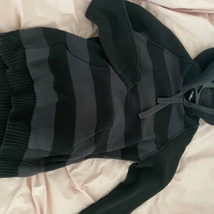 Svart och grå randig hoodie - Säljer en svart och grå randig hoodie . Den har en klassisk design med huva och ribbade muddar. Storlek L men den är som en s skulle jag säga