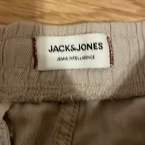 Beige byxor från Jack & Jones storlek XL - Säljer ett par bekväma beige byxor från Jack & Jones med snörning i midjan. Helt nya 
