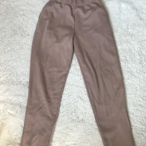 Beige mjukisbyxor från Bik Bok - Säljer ett par bekväma beige mjukisbyxor från Bik Bok i storlek XS. Byxorna har en elastisk midja för extra komfort och är perfekta för en avslappnad stil. Perfekta för mysiga dagar hemma eller en avslappnad dag ute.