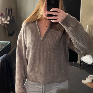 Beige ribbad tröja med dragkedja - Säljer en mysig beige ribbad tröja med dragkedja framtill. Tröjan har långa ärmar och en bekväm passform, perfekt för kyligare dagar.