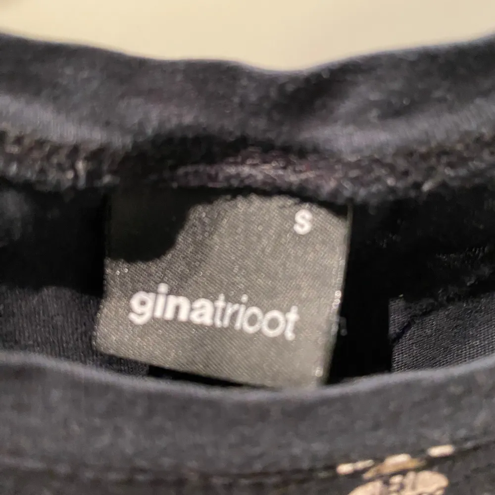 Cool svart t-shirt från Gina Tricot med ett unikt tryck av en kunglig figur och texten 'Never Mind Royal'. Perfekt för en avslappnad stil med en twist. Kortärmad och i mjukt material.. T-paidat.