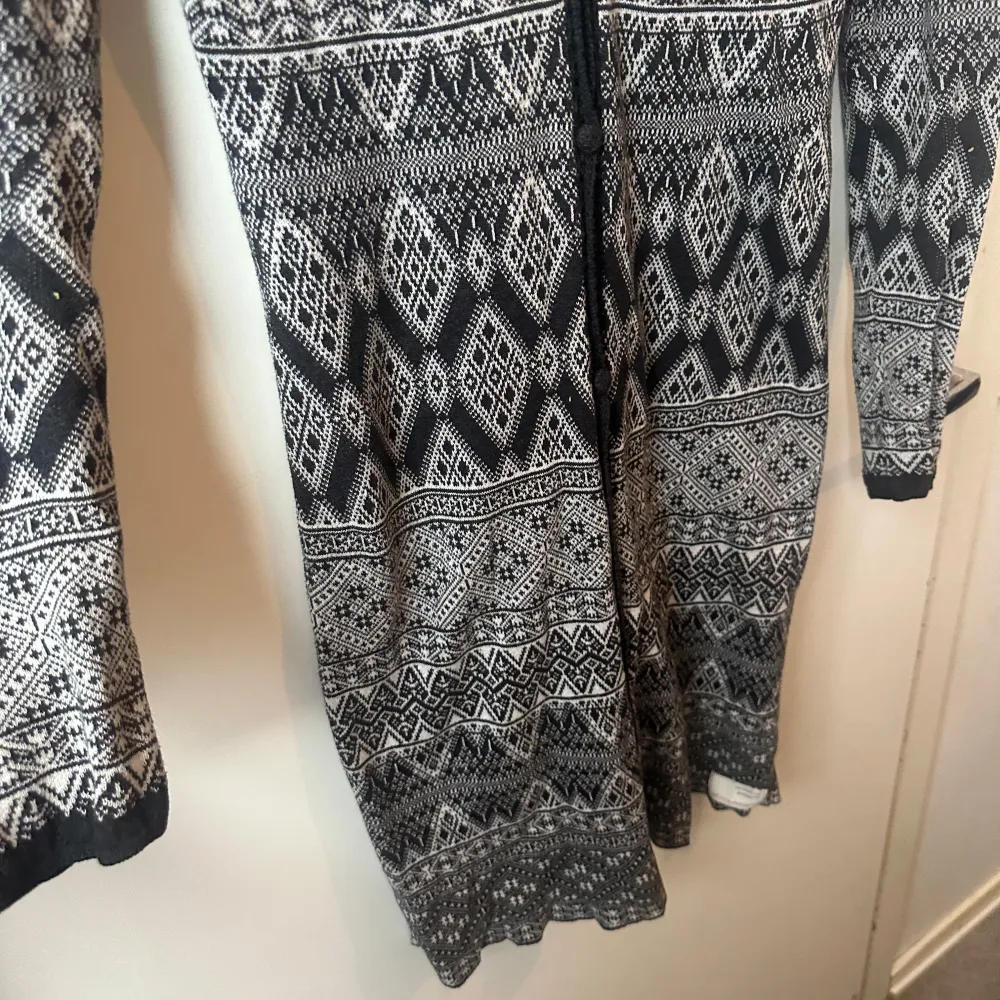 Snygg lång kofta i svart, grått och vitt med ett detaljerat mönster. Koftan har långa ärmar och en djup v-ringning. Perfekt för kyliga dagar när du vill ha något stilrent och bekvämt.Från märket Odd Molly i storlek 1 som enligt deras storleksguide motsvarar en storlek S. Mycket fint skick, jag hittar inga synliga anmärkningar eller defekter. Kan ha lite ytludd. . Neuletakit & Villapaidat.