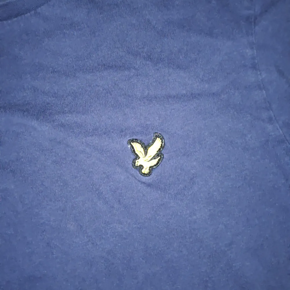 Säljer en blå t-shirt från Lyle & Scott med ett broderat logga på bröstet. Tillverkad i 100% bomull. Perfekt för en avslappnad stil.. T-paidat.