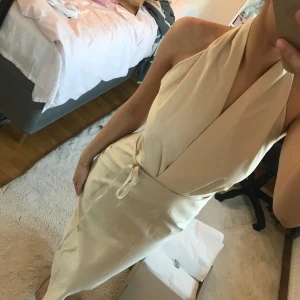 Beige halterneck klänning - Säljer en klänning med öppen rygg och slits bak från Zara.  Ny med prislapp, aldrig använd.  Defekt, knappt synlig, visas i bild 4.  Strl Xs.