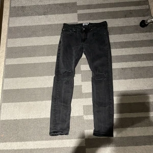 Svarta jeansbyxor från 157 - Snygga svarta jeansbyxor från 157 i storlek M. Byxorna har en slim passform med slitna detaljer vid knäna. Perfekta för en trendig look. Använda bara några gånger