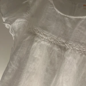 Vit blus från Gina Tricot - Säljer en söt vit blus från Gina Tricot i storlek 146/152. Blusen har korta ärmar och fina detaljer med volanger och spets. Perfekt för somriga dagar! 🌸
