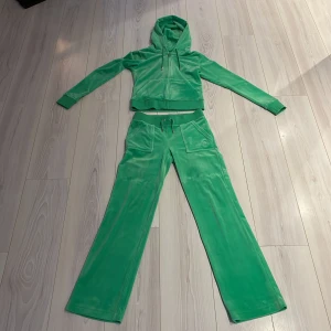 Grön velour hoodie och byxor från Juicy Couture - Säljer en snygg grön velour hoodie och matchande byxor från Juicy Couture. Storleken är XS, var och en för 500kr (båda för 1000kr) otroligt snygg och fin. Hoodien har dragkedja och snörning i luvan, medan byxorna har resår och snörning i midjan. Perfekt för en avslappnad stil 💚