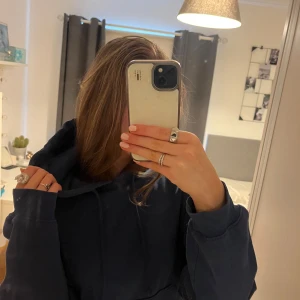 Mörkblå hoodie - Säljer en mörkblå hoodie med en klassisk design. Den har en stor huva och långa ärmar, perfekt för en avslappnad stil. Passar bra till jeans eller andra casual outfits.