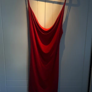 Röd klänning med drapering - Snygg röd klänning med smala axelband, klyvning och öppen rygg. 