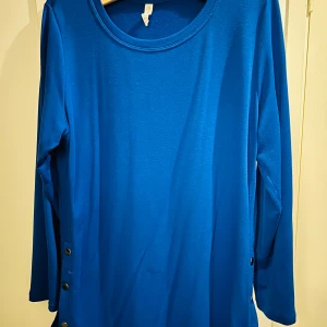 Blå långärmad tröja från Ideology - Säljer en snygg blå långärmad tröja från Ideology. Den har en enkel designu med knappar på sidan som ger en extra touch. Perfekt för både vardag och lite finare tillfällen. Materialet känns mjukt och skönt mot huden. Passar perfekt till jeans eller kjol!