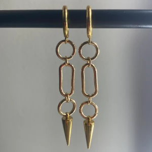 Guldiga örhängen  - Det är ett par guldiga örhängen 