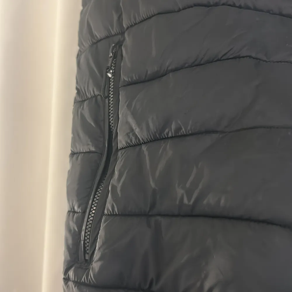 Säljer en svart dunväst från Bershka i storlek S. Västen har en dragkedja framtill och två praktiska fickor med dragkedjor. Perfekt för höst och vår när du vill hålla dig varm men ändå se stilren ut. Passar bra till både vardag och lite mer avslappnade tillfällen.. Takit.