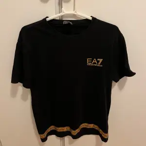 Ea 7 T-shirt svart och guld i storlek s. Finns lute tvätt skador på det guldiga nertill på tröjan. Typ som små sprickor i guldet(se bild)