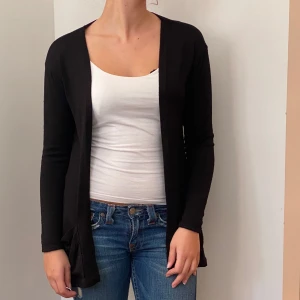 Svart kofta från H&M - Säljer en stilren svart kofta från H&M i storlek 170. Den är perfekt för både vardag och fest med sin enkla design och långa ärmar. Materialet är mjukt och bekvämt, vilket gör den idealisk för höst och vår. Passar bra över en topp eller klänning för en avslappnad look.
