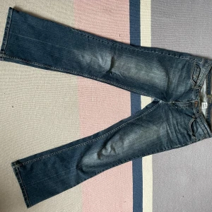 Blå bootcut jeans med broderade fickor - Säljer ett par jättesnygga mörkblåa, lågmidjade, bootcut jeans med fina detaljer broderade på bakfickorna. Säljer då de tyvärr är för korta för mig :( (jag är 174cm) Innerbenslängd: 79cm