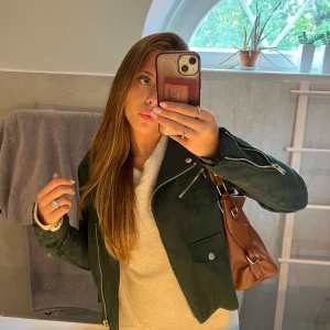 Mörkgrön jacka från ONLY - Säljer en snygg mörkgrön jacka från ONLY. Den har en cool bikerstil med flera dragkedjor och knappar i silver. Jackan är perfekt för höst och vår, och ger en edgy touch till vilken outfit som helst. Den är i bra skick och redo för nya äventyr!