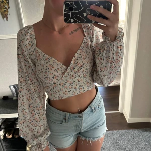 Blommig långärmad  - En blommig långärmad topp,omlot över brösten, går att ha både off shoulder och vanligt, dragkedja bak