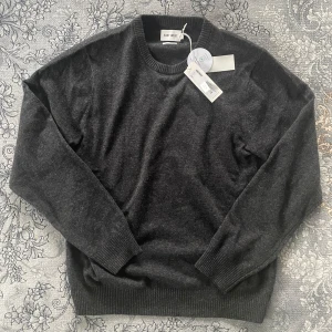 East West Tröja - Mörkgrå tröja från Brothers, märket East West. Gjord av 100% lambswool, helt oanvänd. Storlek L men passar även M. Mjuk, varm och perfekt för alla tillfällen. Sprillans ny tröja nypris 1000kr för endast 225kr!🔥💫Ps. Pris kan diskuteras vid snabb affär!