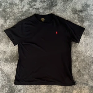 Svart Ralph Lauren t-shirt - Säljer skit snygg svart polo tröja för billigt pris. Tröjan är i fint skick dock har den två svårsynliga små hål. Den är storlek S passar även M. Priset är ej hugget i sten🤩🤝 