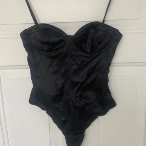 Svart body från Zara - Super snygg svart fest body från Zara med tunna axelband och en elegant design. Perfekt för att skapa en stilren look. Helt ny, oanvänd och prislapp kvar! Säljer då den inte passade. 