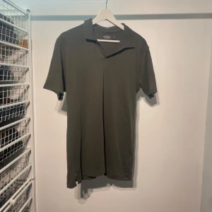 Grön pikétröja - Säljer en stilren grön pikétröja med klassisk krage. Perfekt för en avslappnad men ändå snygg look. Kortärmad design som passar bra till både jeans och shorts.