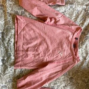 Rosa träningstopp från gymshark - Säljer en rosa långärmad träningstopp från gymshark. Tröjan har en enkel design med ett litet logotryck på bröstet. Andvänt fåtal gånger och är i mycket bra skick! Ord pris: 280 kr😊