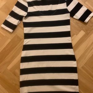 Randig klänning med trekvartsärm - Snygg svartvit randig klänning från Filippa K med trekvartsärm. Perfekt för en stilren look. Klänningen har en klassisk passform och är gjord i stretchig bomull.