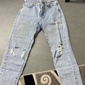 Mom jeans - Snygga ljusa jeans med coola slitningar på benen från Perfect Jeans. De har en klassisk femficksdesign och är perfekta för en avslappnad stil. Passar bra till sneakers eller boots.