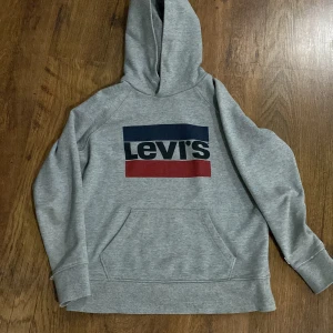 Grå hoodie från Levi's - Säljer en grå hoodie från Levi's som jag har haft ganska länge. Den är lite sliten i högra ärmen men det är inget hål.
