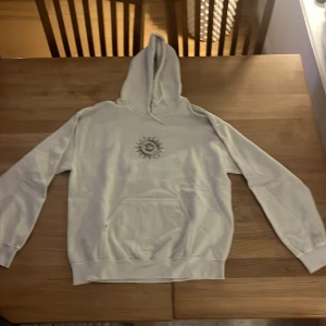 Vit hoodie med tryck - Säljer en vit hoodie med ett unikt tryck av en kompassros på både fram- och baksidan. Hoodien har långa ärmar och en klassisk huva. Perfekt för en avslappnad stil. Är från kurvan ourfiters och inte använd mycket. Storlek XS men passar S med inga problem 