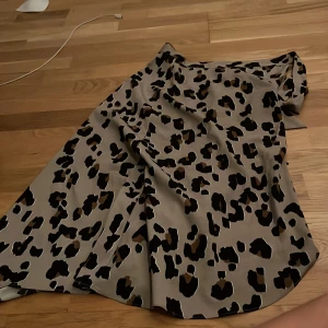 Leopardmönstrad kjol - Snygg leopardmönstrad kjol i beige och svart. Perfekt för att sticka ut med ett djärvt mönster. Kjolen har en avslappnad passform och är idealisk för både vardag och speciella tillfällen.
