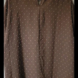 Brun blus med småmönster - Snygg brun blus med småmönster och korta ärmar. Perfekt för en avslappnad stil. Blusen har en lös passform och är tillverkad i ett lätt material.❤️
