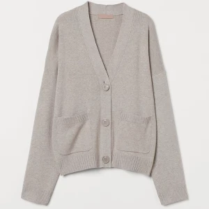 Beige kofta med knappar - Säljer en stilren beige kofta med knappar framtill. Den har en v-ringad design och två praktiska fickor. Perfekt för lager-på-lager under kyligare dagar. Passar både till jeans och kjol. Ingår en topp till