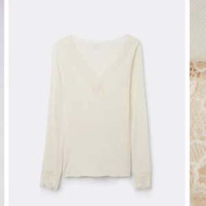 Vit intimissimi topp med spetsdetaljer - Elegant vit långärmad topp med v-ringning och vackra spetsdetaljer vid hals och ärmslut. Perfekt för en stilren look. Från intimissimi 