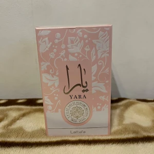 Yara Eau de Parfum från Lattafa - Upptäck Yara Eau de Parfum från Lattafa, en elegant doft i en vacker rosa förpackning med blommönster. Perfekt för den som söker en unik och sofistikerad doftupplevelse. Innehåller noter av limonen och bergamott för en fräsch känsla men även jordgubbar!! Perfekt att laya den med andra parfymer! 